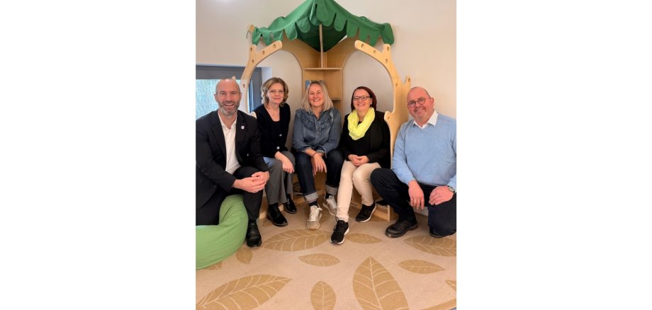 Zwei Männer und drei Frauen sitzen nebeneinander in einer Kita