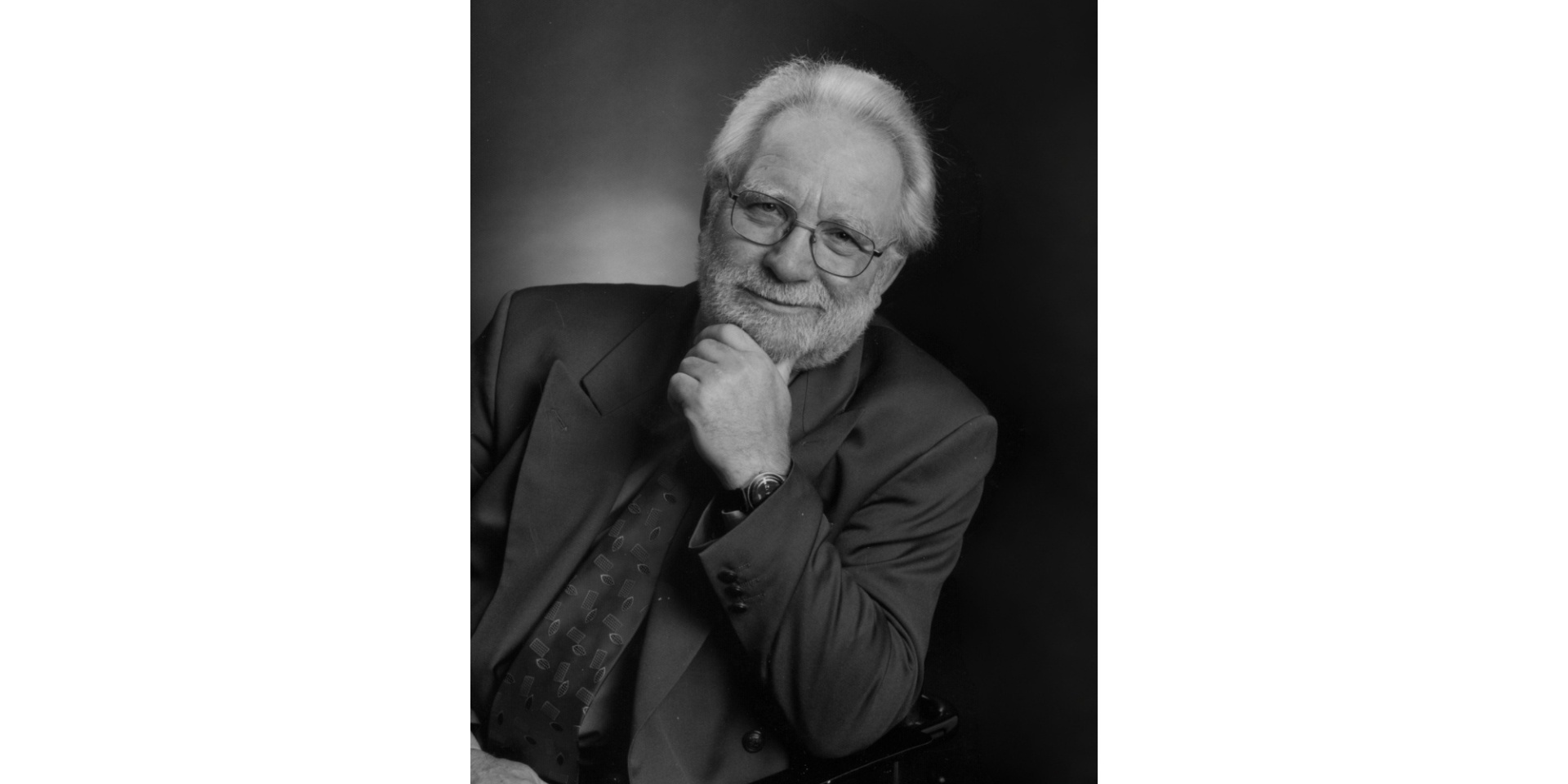 Älterer Mann mit weißen Haaren und in einem dunklen Anzug lächelnd