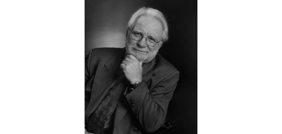 Älterer Mann mit weißen Haaren und in einem dunklen Anzug lächelnd