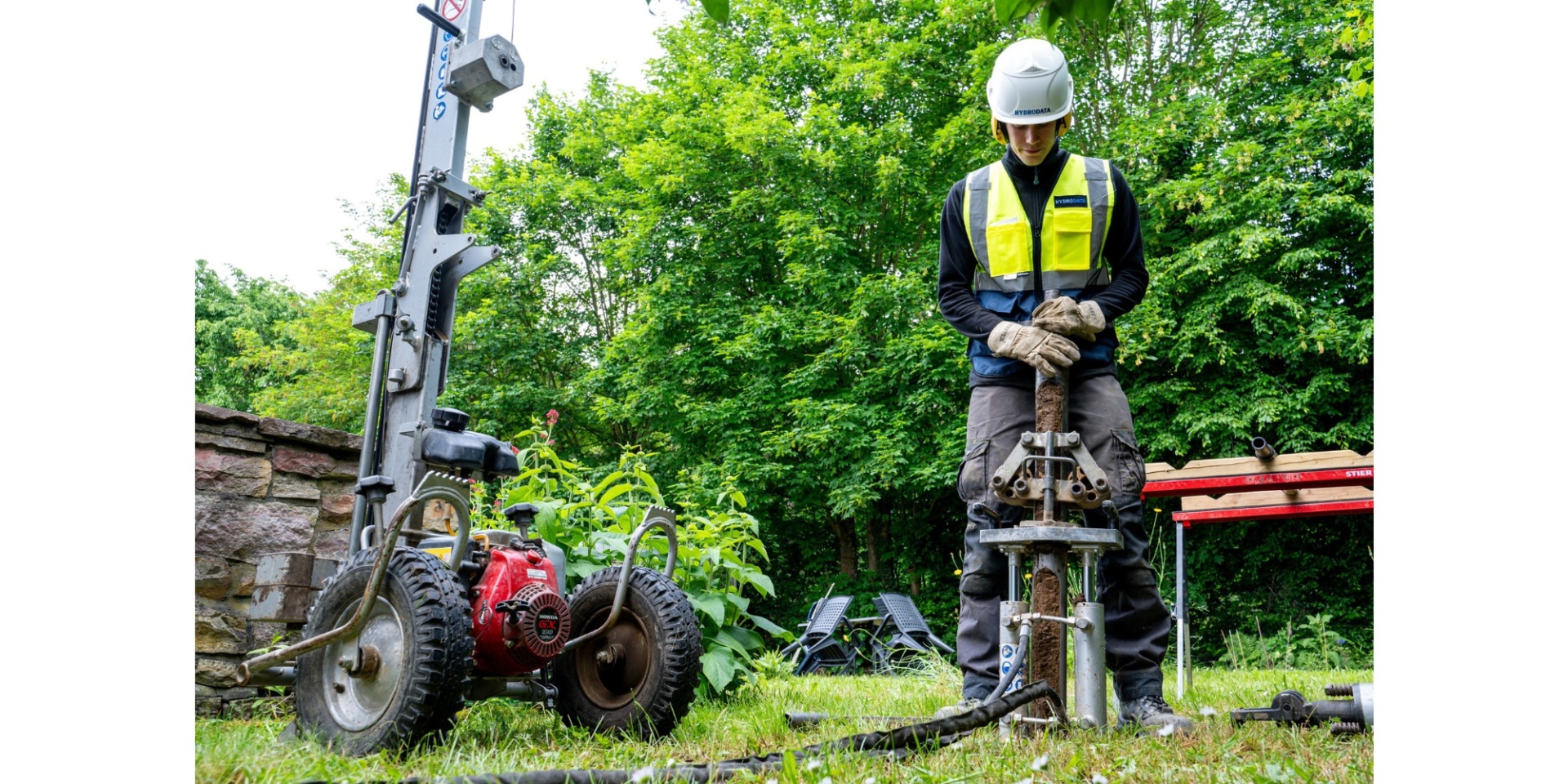 Arbeiter mit neongelber Warnweste stehend mit einem Kleinrammbohrer