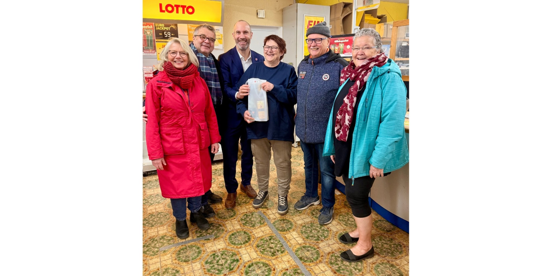 Drei Frauen und drei Männer stehend in einem Ladengeschäft.