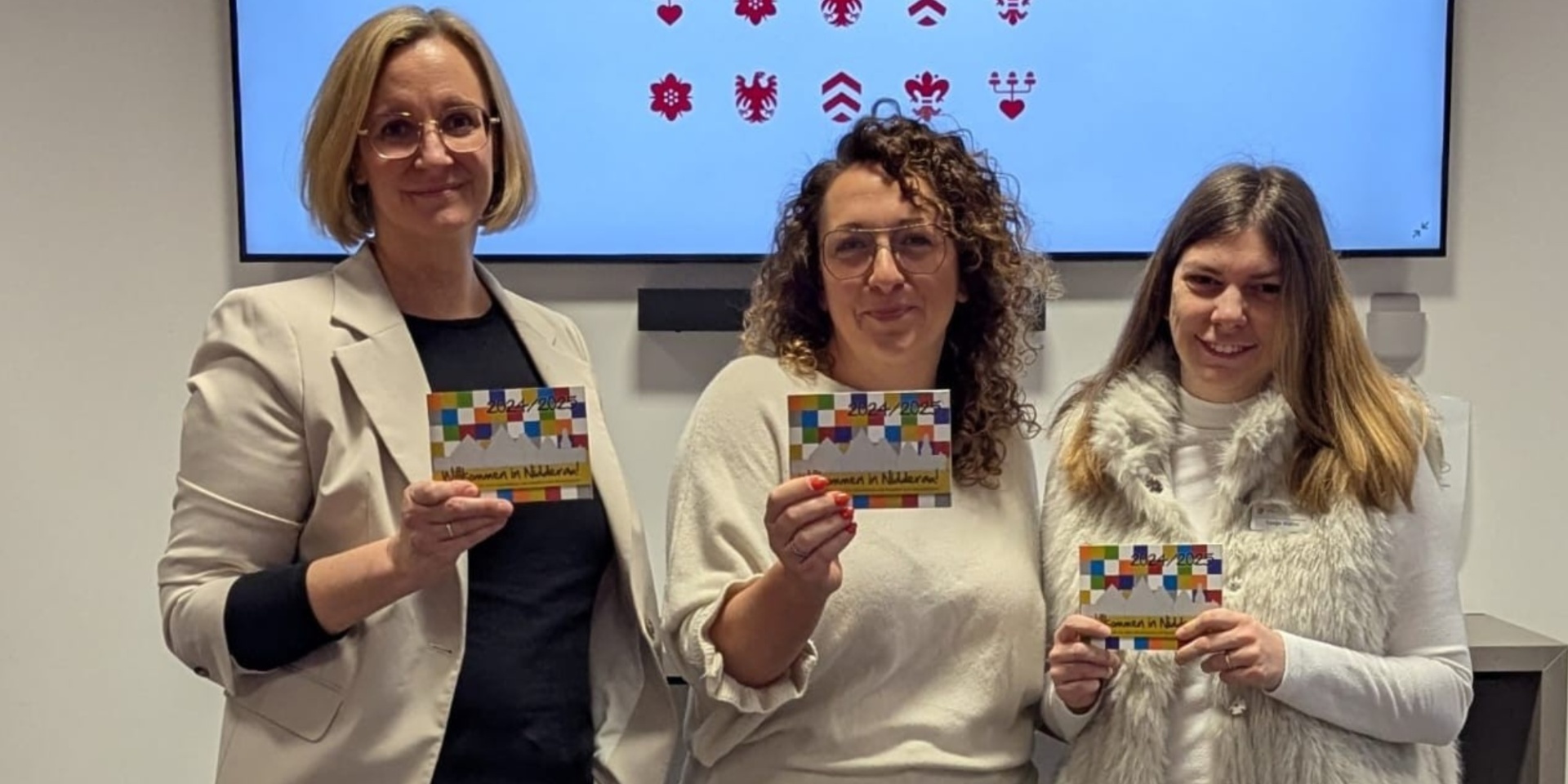 Drei Frauen nebeneinander stehend, halten jeweils ein kleines Heft in der Hand