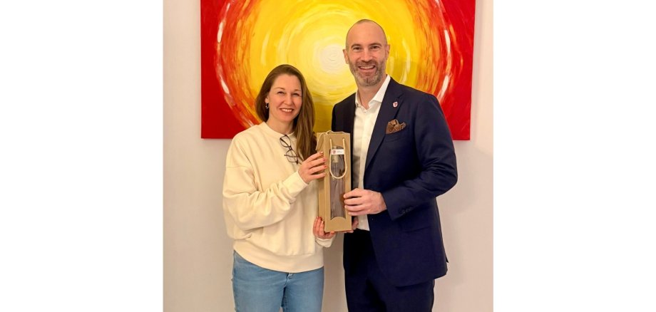 Eine Frau und ein Mann stehend und lächelnd vor einem Gemälde.