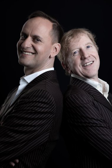 Zwei Männer in schwarzen Nadelstreifenanzügen stehen Rücken an Rücken