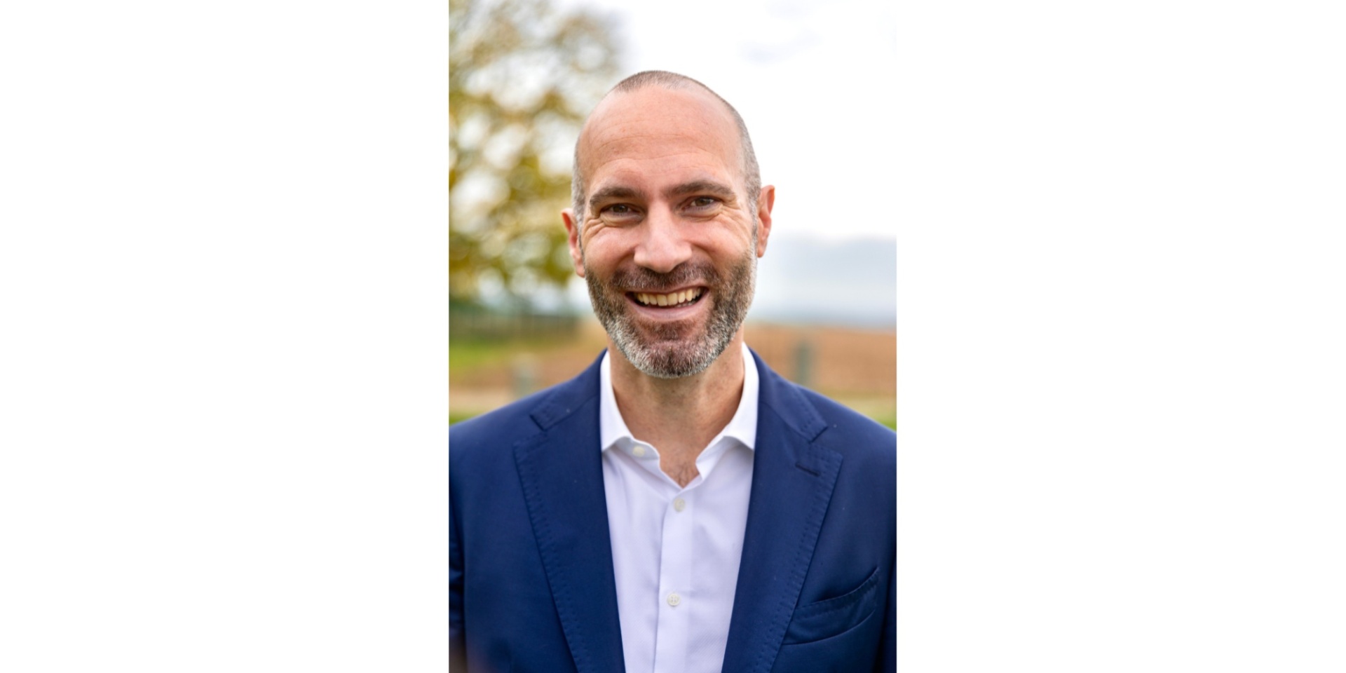 Mann mit weißem Hemd und blauem Sacko lächelnd