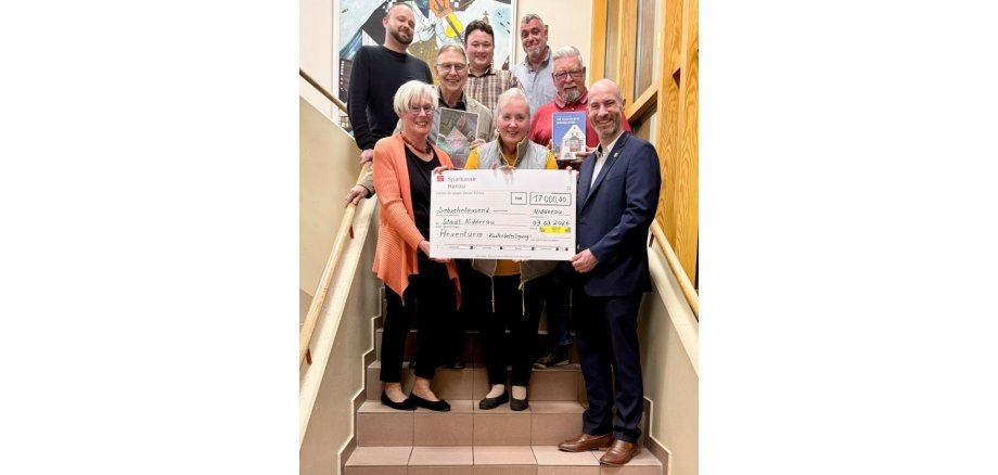 Mehrere Personen auf einer Treppe stehend, einen großen Spendenscheck haltend