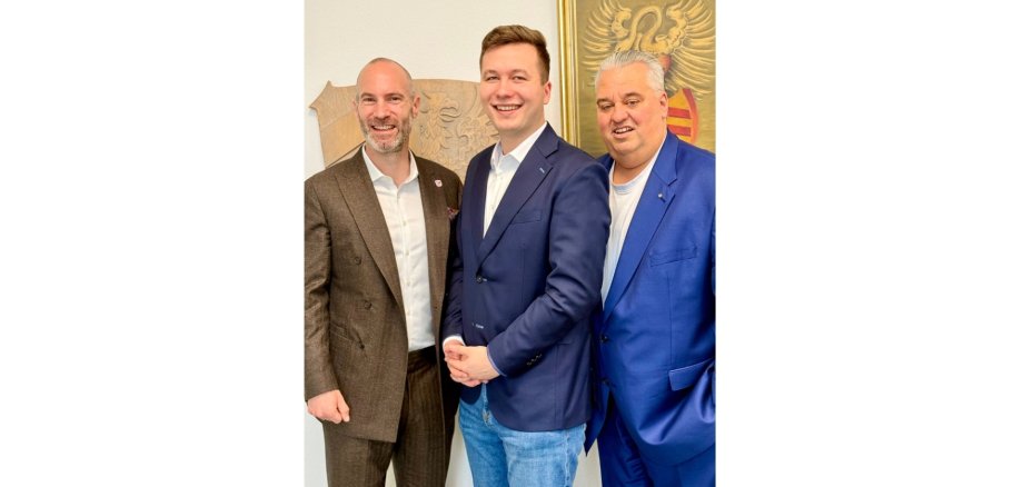 Drei Männer in Anzügen stehend nebeneinander