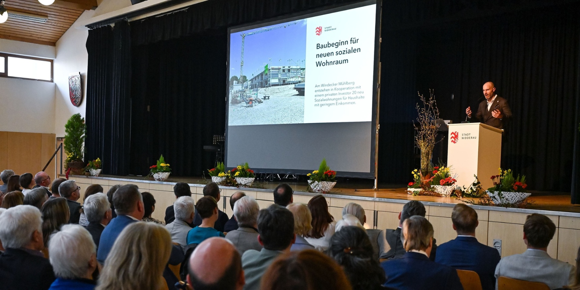Schwarze Bühne mit einer Person darauf und Publikum davor