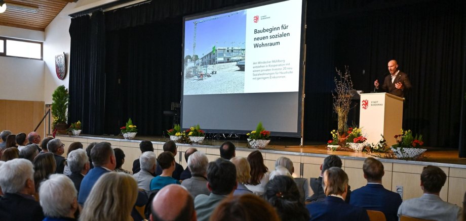 Schwarze Bühne mit einer Person darauf und Publikum davor