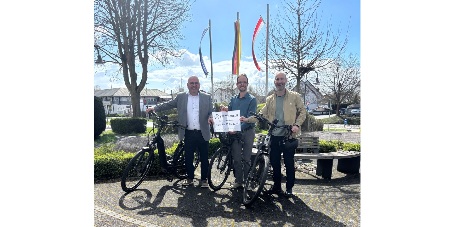 Drei Männer mit drei Fahrrädern stehend.