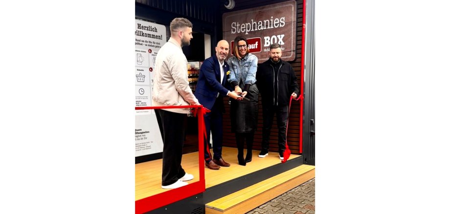 Mehrere Personen weihen einen Supermarkt-Container ein