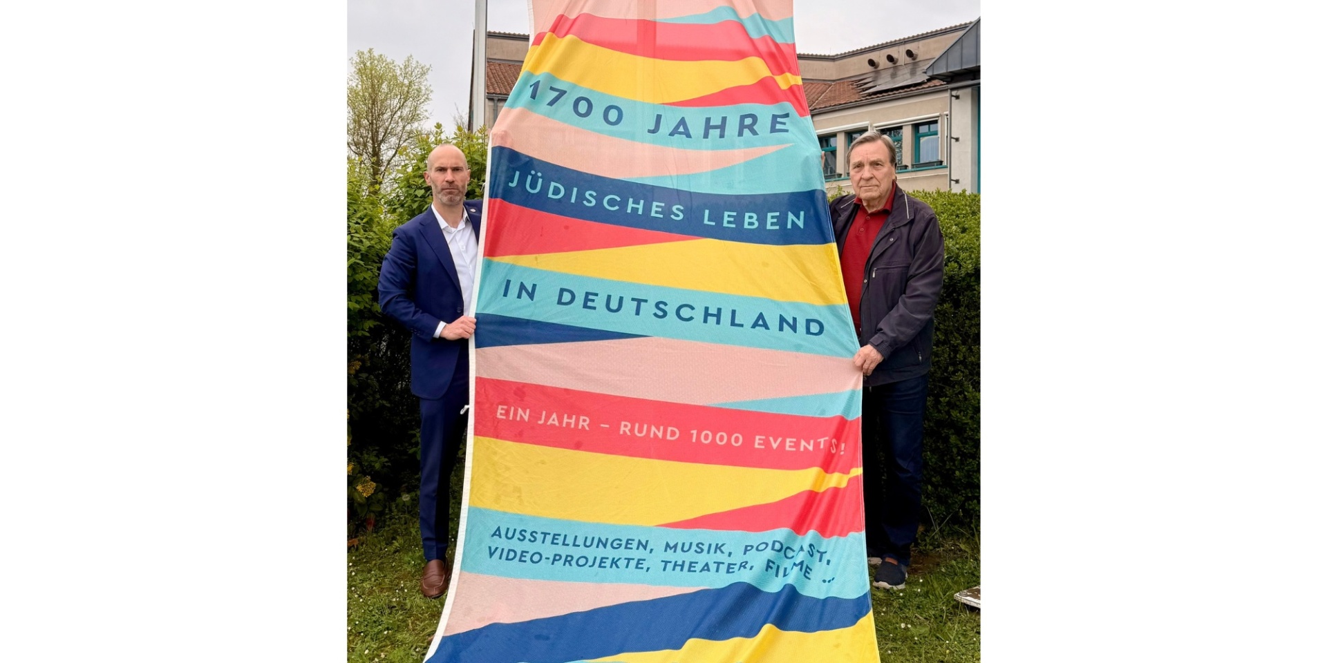 Zwei Männer stehend, die eine große Fahne halten.