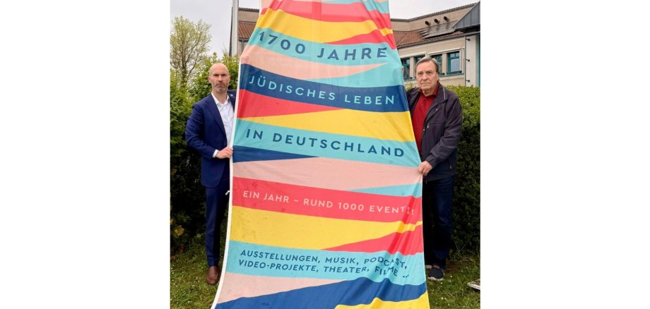 Zwei Männer stehend, die eine große Fahne halten.