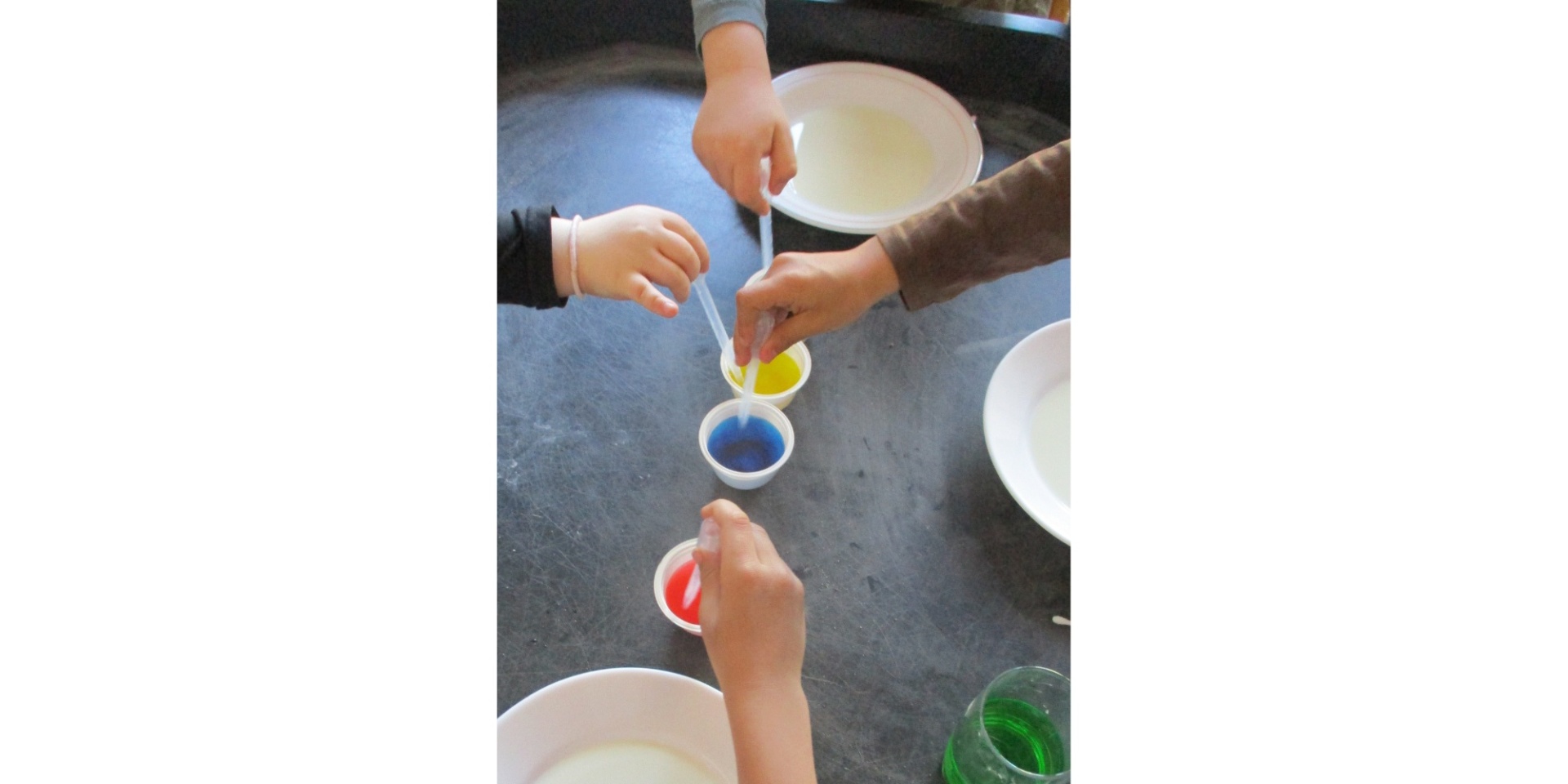 Zwei Kinderhände mit Farben auf einem Tisch