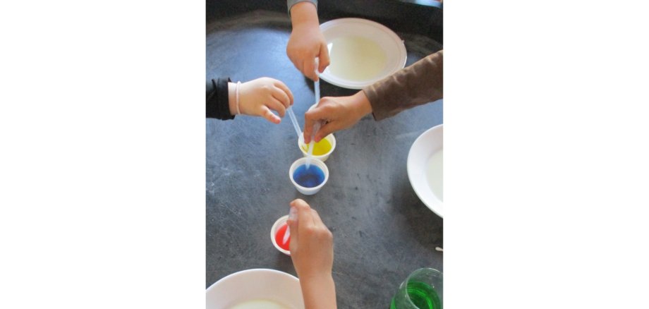 Zwei Kinderhände mit Farben auf einem Tisch