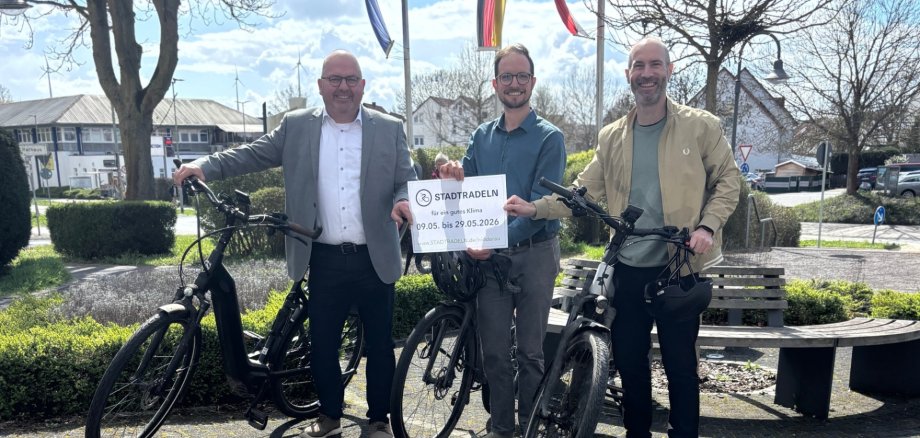 Drei Männer mit jeweils einem Fahrrad stehen nebeneinander