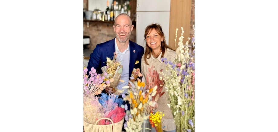 Ein Mann und eine Frau hinter Trockenblumen
