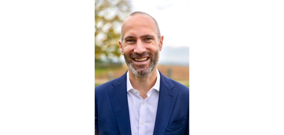 Mann in einem blauen Anzug mit weißem Hemd lächelnd