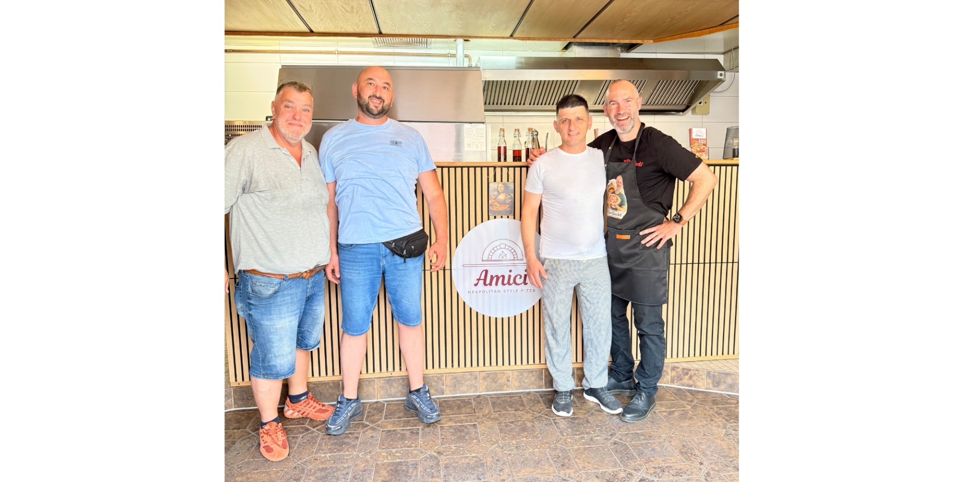 Vier Männer stehend in einem Lokal.