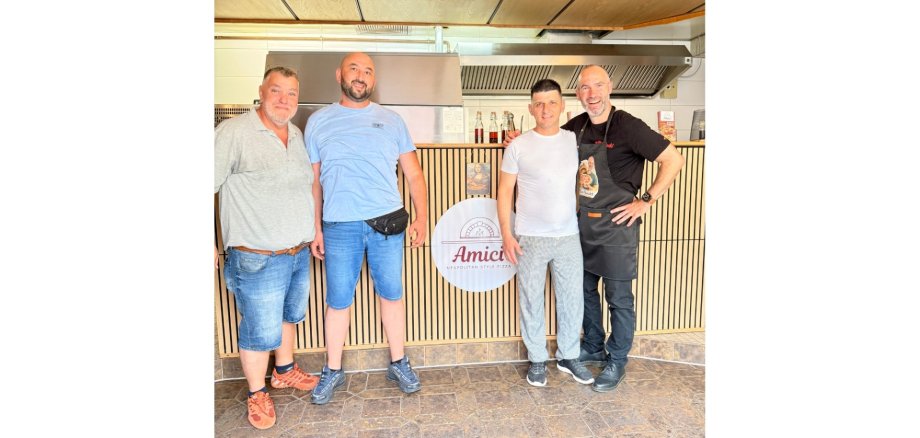 Vier Männer stehend in einem Lokal.