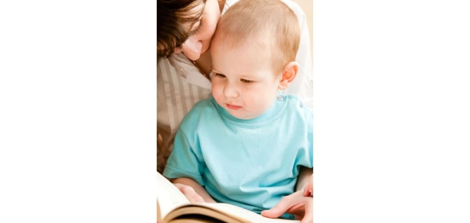 Mutter schaut sich mit einem Kleinkind ein Buch an