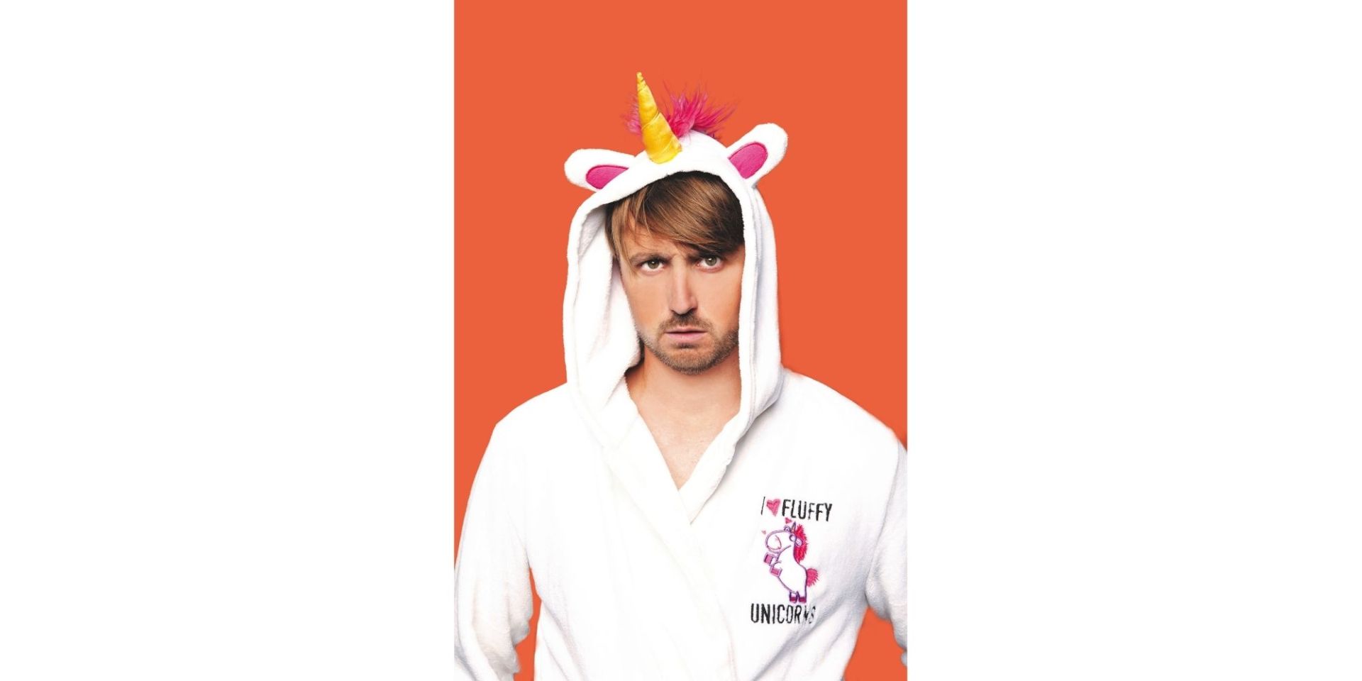 Mann in einem Einhorn-Kostüm vor orange-farbenem Hintergrund