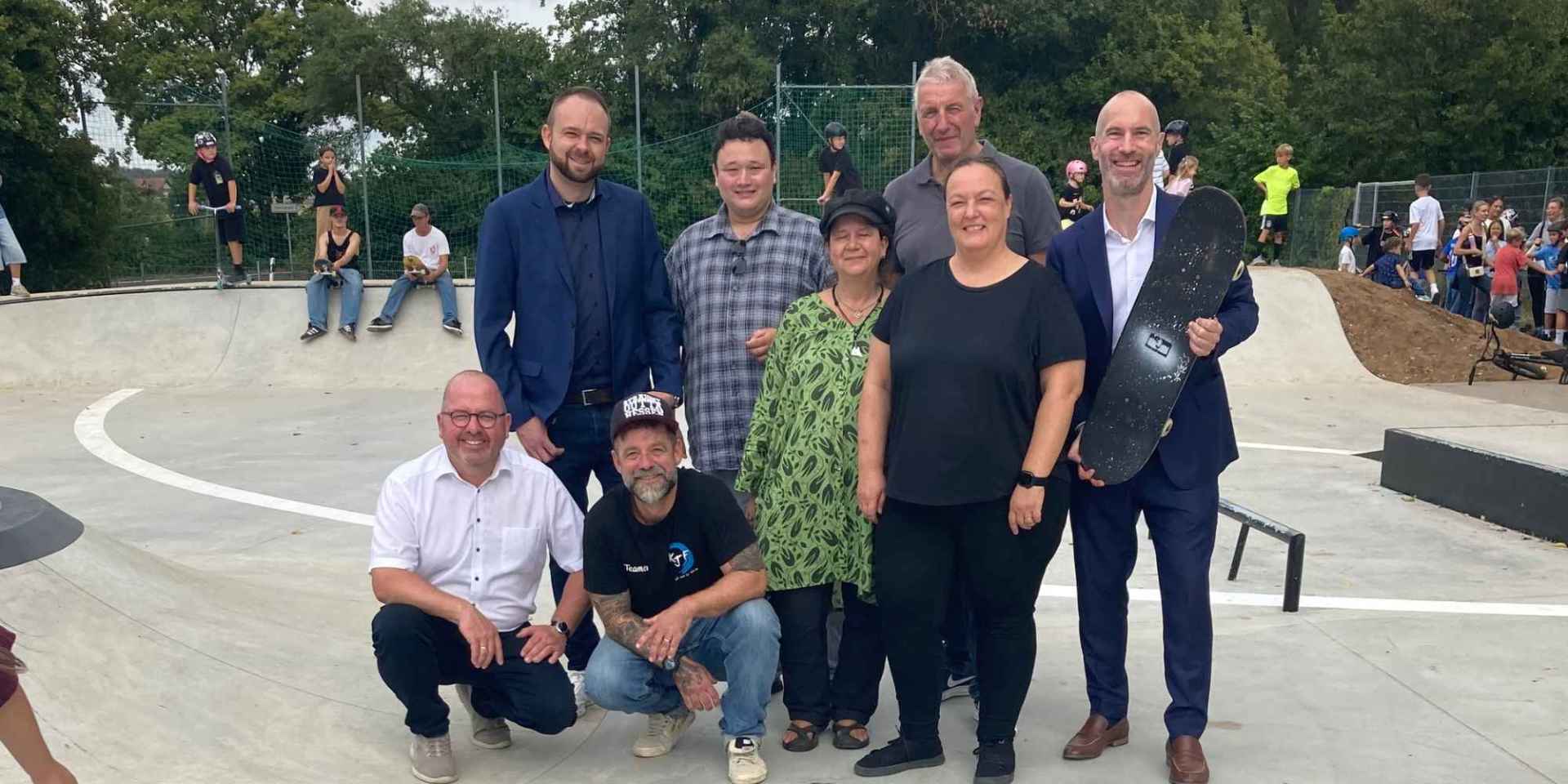 Mehrere Erwachsene stehend auf einer neu errichteten Skateranlage