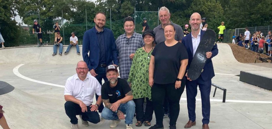 Mehrere Erwachsene stehend auf einer neu errichteten Skateranlage