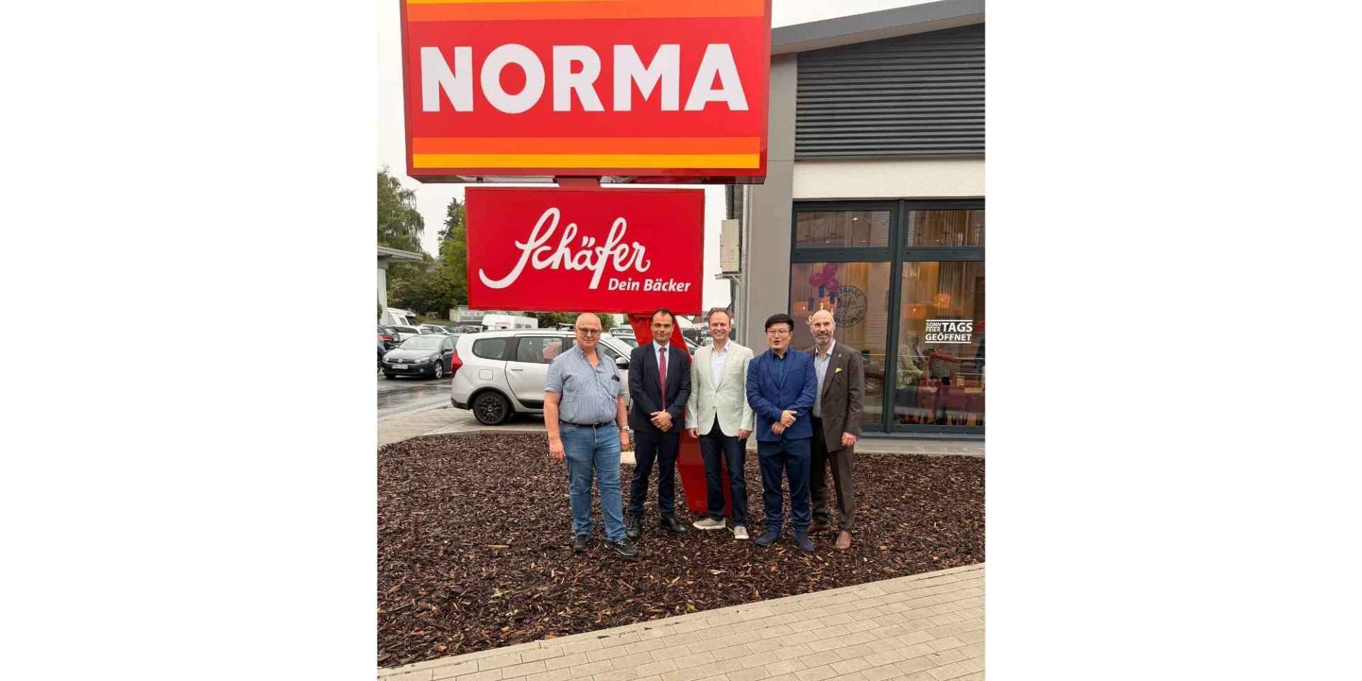 Fünf Männer stehend vor einem Supermarkt