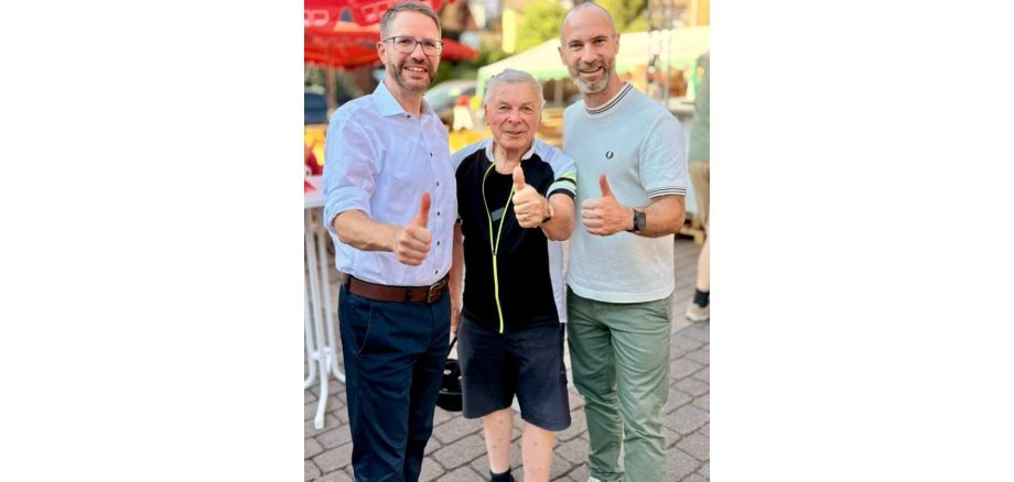 Drei Männer stehend nebeneinander mit jeweils einem erhobenen Daumen