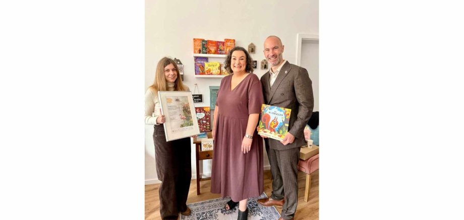 Zwei Frauen und eine Mann stehen nebeneinander in einer Buchhandlung