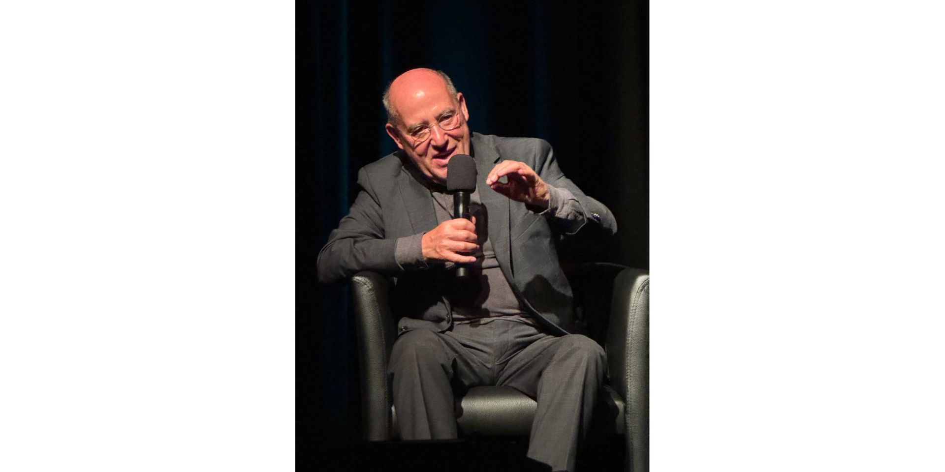 Ein sitzender Mann mit Mikrofon.