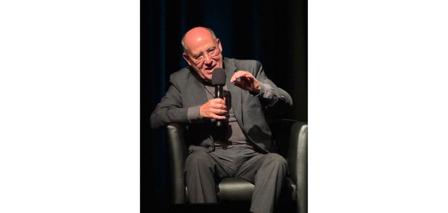 Ein sitzender Mann mit Mikrofon.