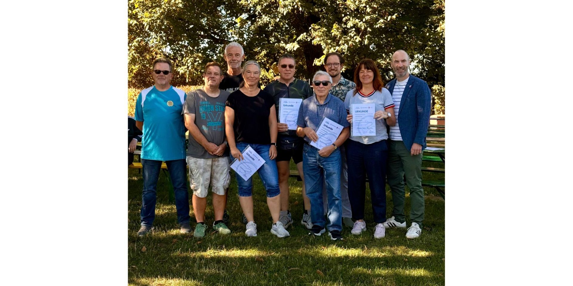 Zwei Frauen und sieben Männer stehend. Einige der Gruppe haben eine Urkunde in der Hand.