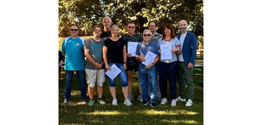Zwei Frauen und sieben Männer stehend. Einige der Gruppe haben eine Urkunde in der Hand.