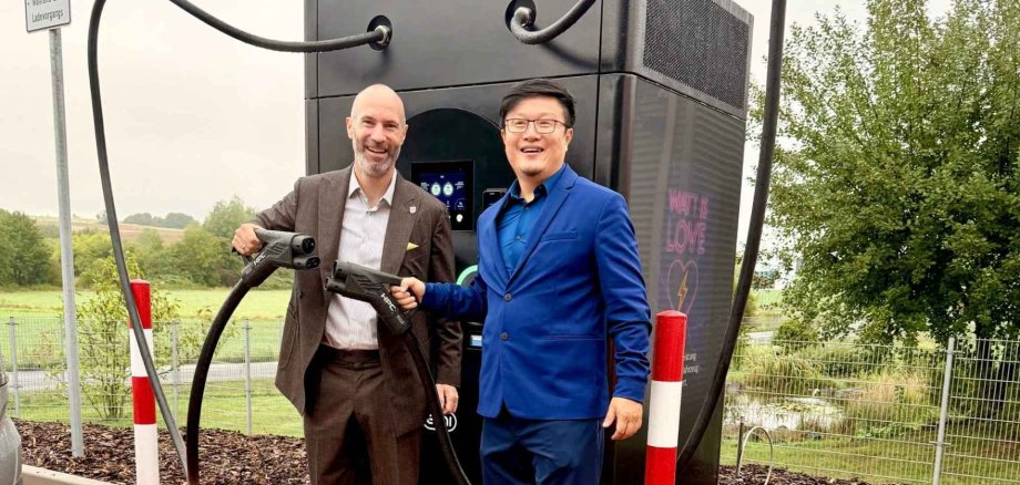 Zwei Männer vor einer Schnellladesäule für Elektroautos