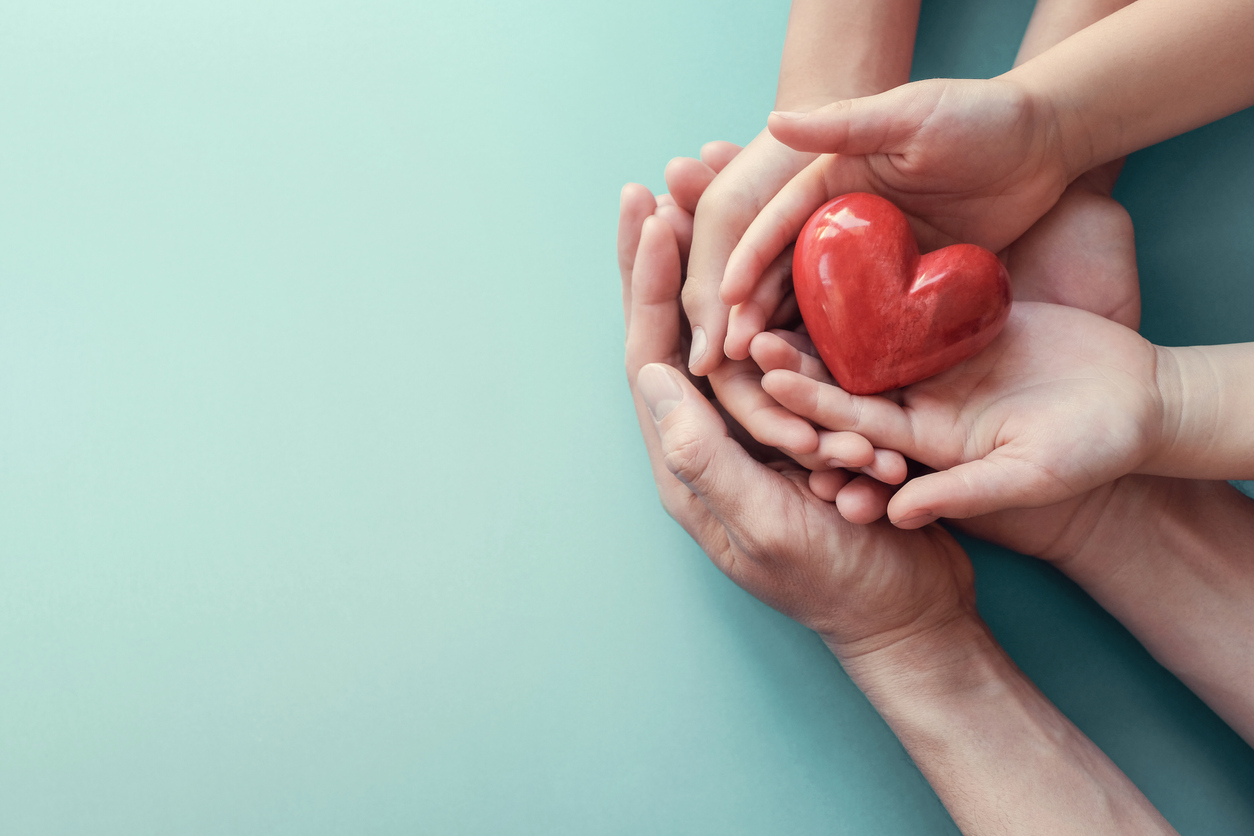 adult and child hands holding red heart on aqua background, heart health, donation, CSR concept, world heart day, world health day, family day Offene Hände halten ein rotes Herz
