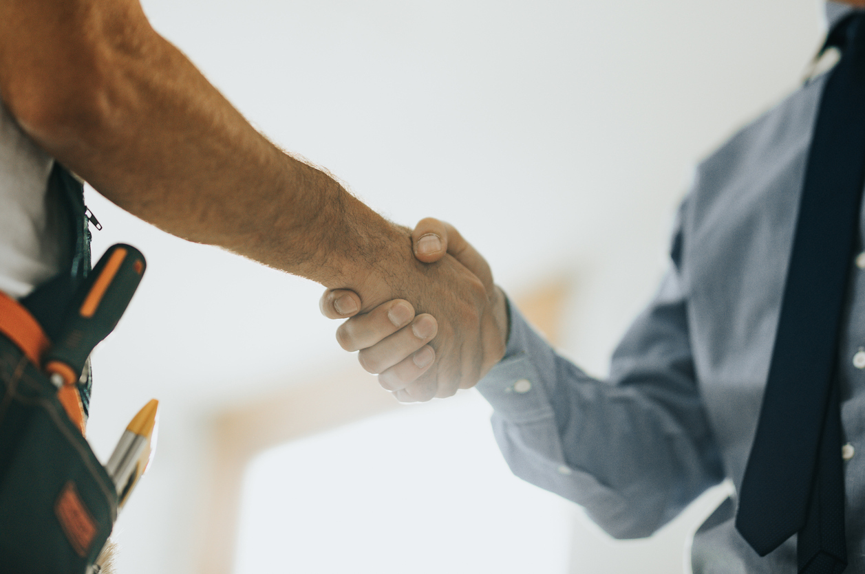 Close up of worker and architect shaking hands at construction site. Hände schütteln