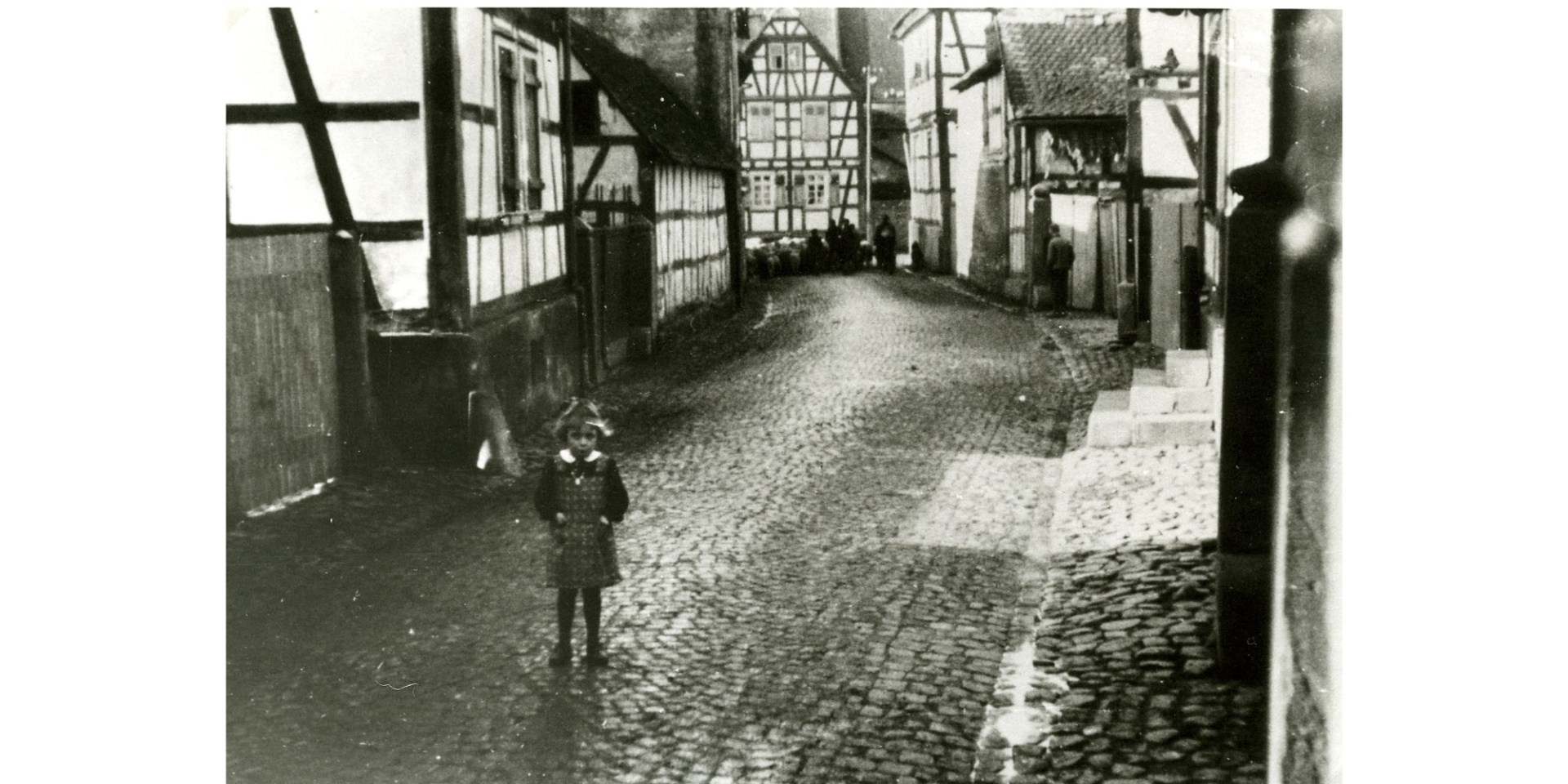 Ansicht Straße Fachwerkhäuser mit Kopfsteinpflaster und einem Mädchen darauf stehend
