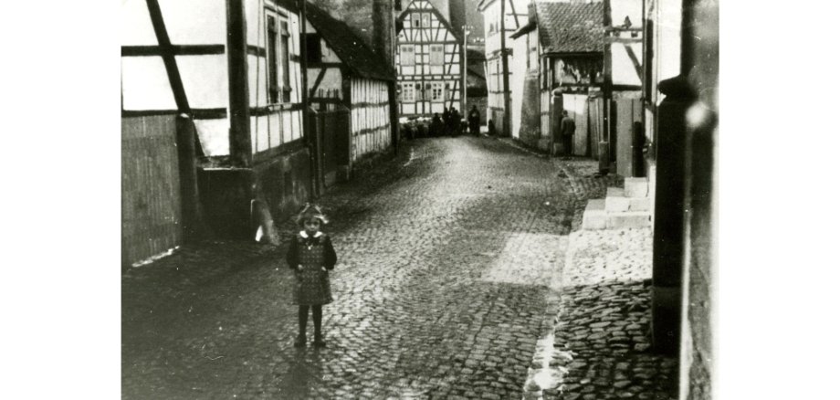 Ansicht Straße Fachwerkhäuser mit Kopfsteinpflaster und einem Mädchen darauf stehend