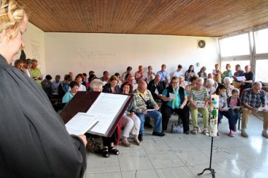 Pfarrerin im Gemeindehaus mit anwesender sitzender Gemeinde