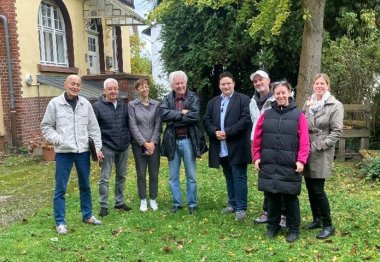 Mehrere Personen nebeneinander stehend vor einem Haus