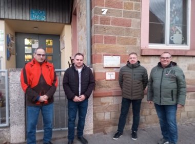 Mehrere Personen nebeneinander stehend vor einem Haus