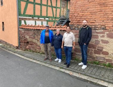 Mehrere Personen nebeneinander stehend vor einem Haus