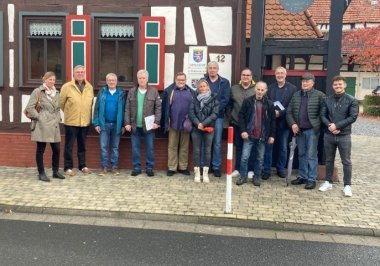 Mehrere Personen nebeneinander stehend vor einem Fachwerkhaus