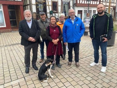 Mehrere Personen nebeneinander stehend vor einer Häuserfassade
